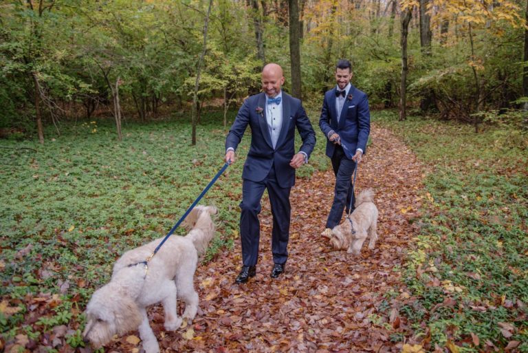 Two grooms walk their dog at their fall wedding at Lord Thompson Manor Thompson CT
