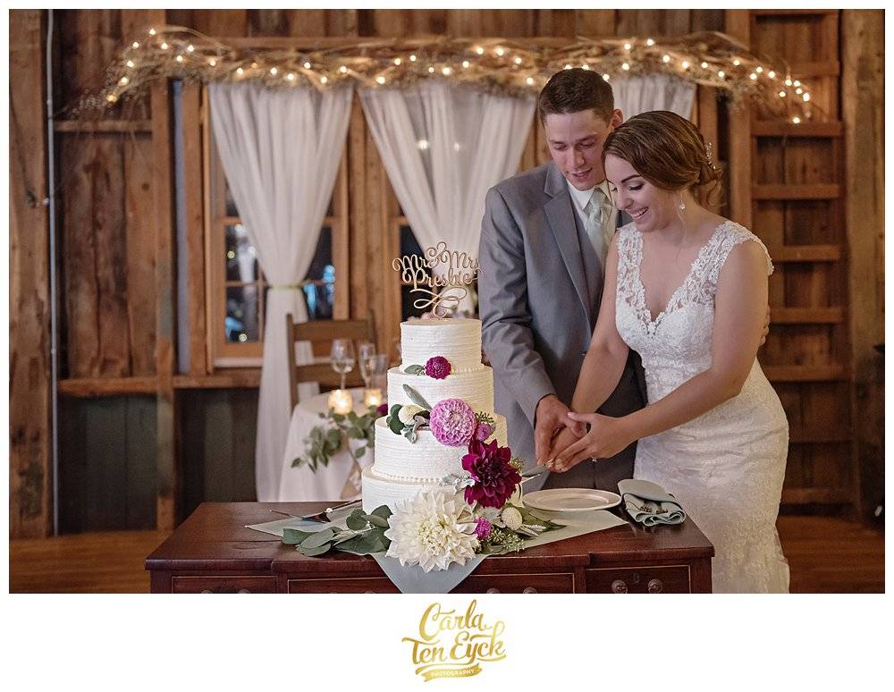 Bride and groom cut their wedding cake with purple flowers at Tyrone Farm, Pomfret CT