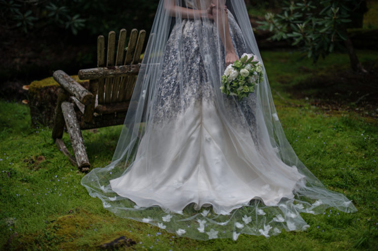 A bride in her veil stands in a mossy glen at Lonesome Valley in Cashiers NC