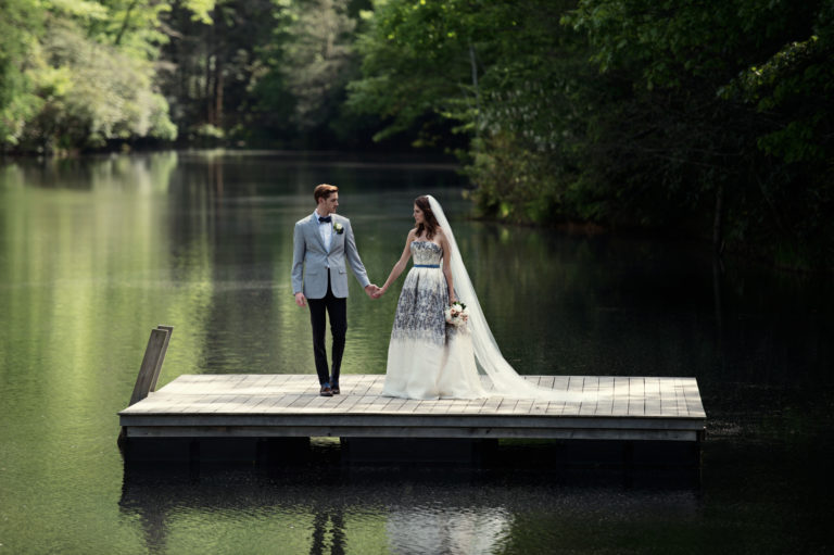 Bride and groom stand on a swim platform in the lake at Lonesome Valley in Cashiers NC