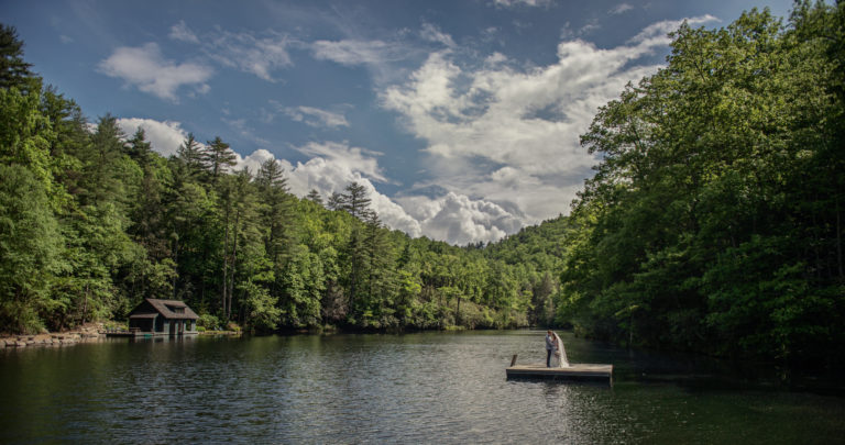 Bride and groom stand on a swim platform on the lake at Lonesome Valley in Cashiers NC