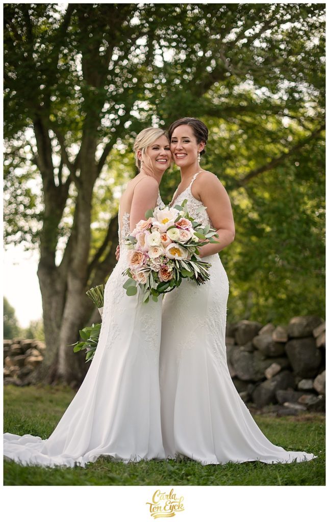 Two brides hold their soft pink wedding bouquets by Hana Floral at Jonathan Edwards Winery