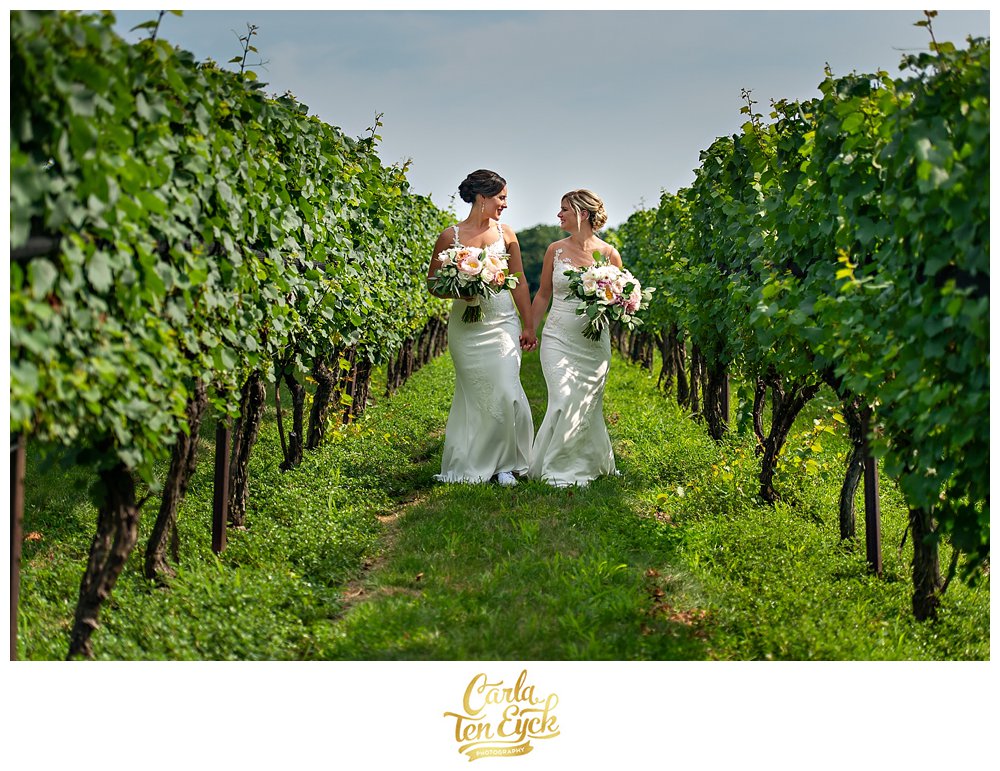 Two brides walk in the vineyard on their wedding day at Jonathan Edwards Winery