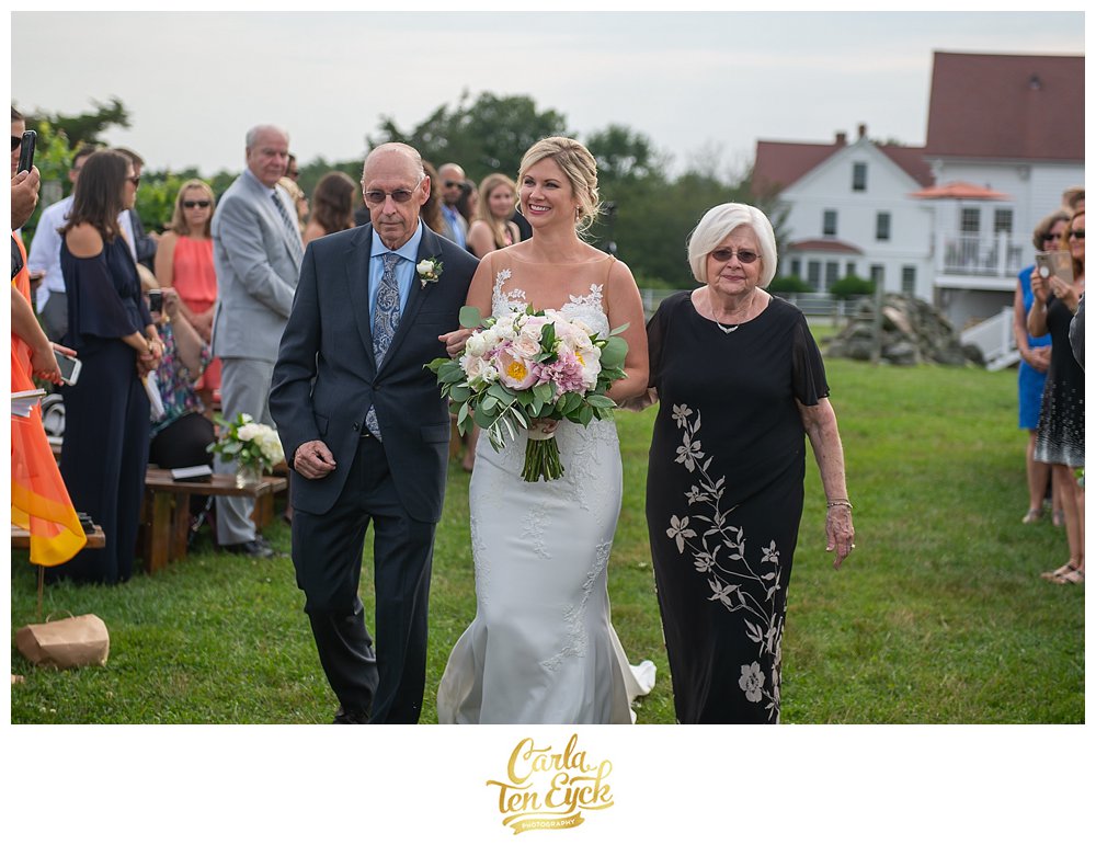 Bride walks down the aisle with her parents at her Jonathan Edwards Winery Wedding