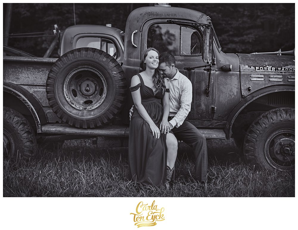 Couple snuggles on a vintage truck at their engagement session at Heritage Homestead in Northford CT