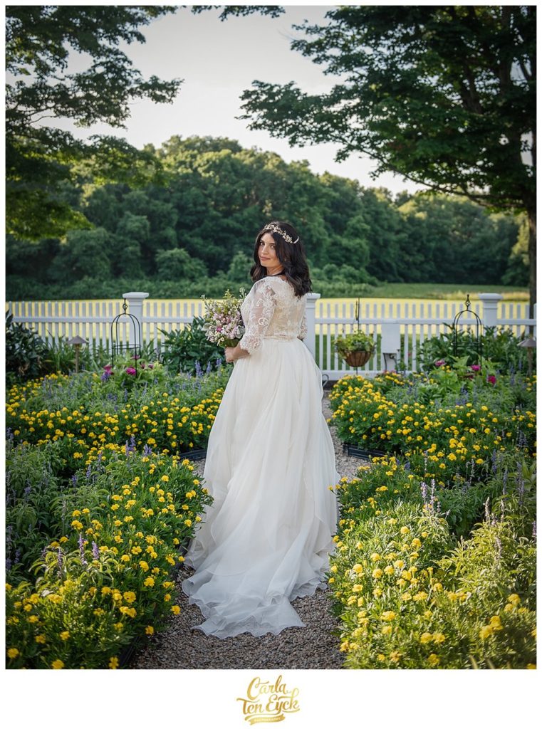 Bride poses in the garden in her wedding gown from Everthine at Smith Farm Garden in East Haddam CT