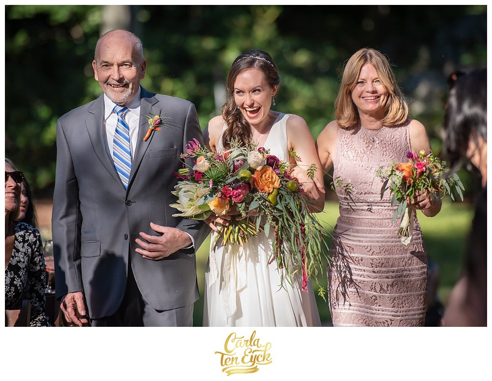 Ecstatic bride walking down the aisle with her parents at her wedding in Norwalk CT