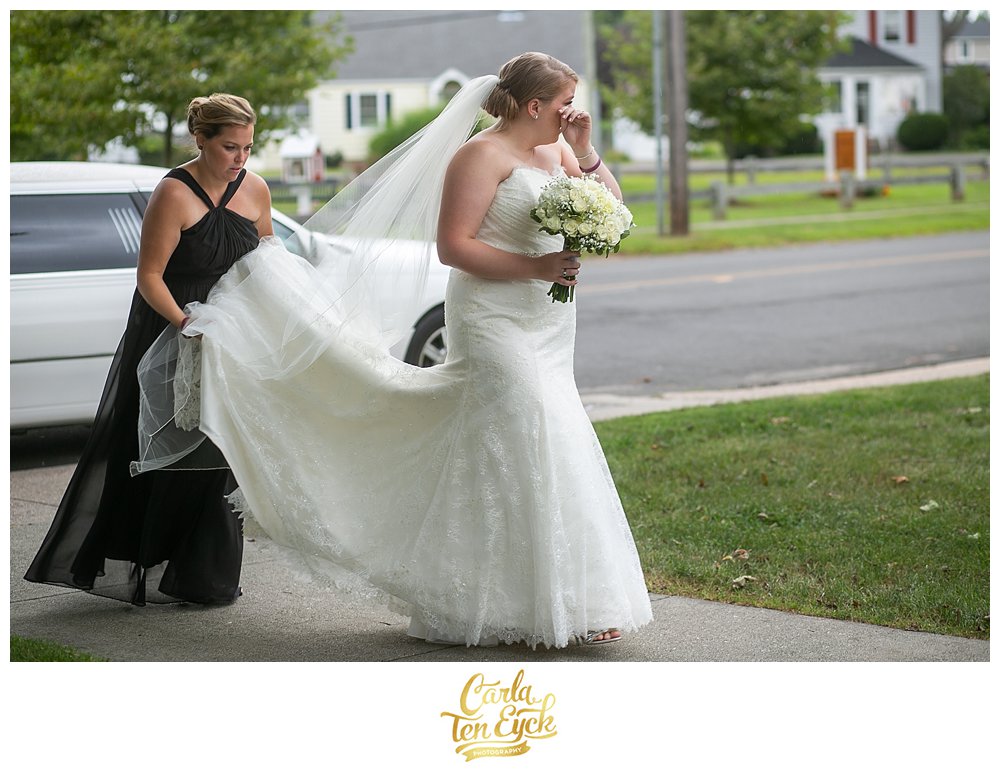 Bride walks into the church and wipes a tear on her wedding day in Lordship CT