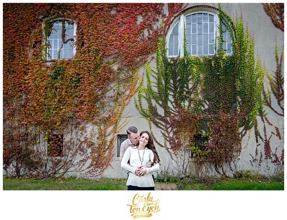 A couple embraces by the ivy during their autumn engagement at Harkness Park Waterford CT
