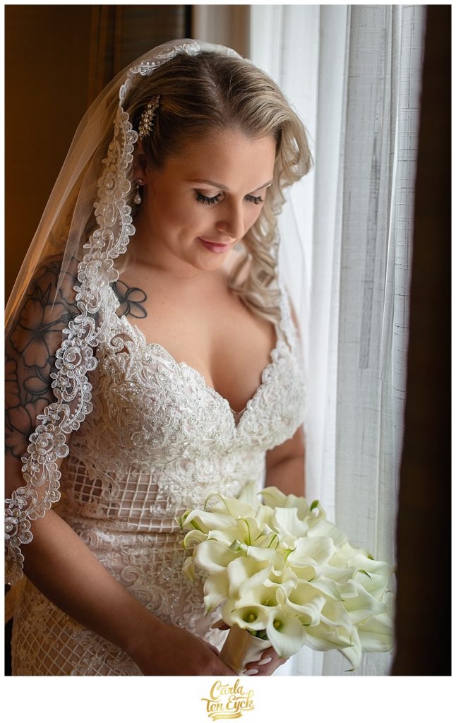 Bride in Stella York wedding gown looks at her calla lily wedding bouquet at the Aria in Prospect CT