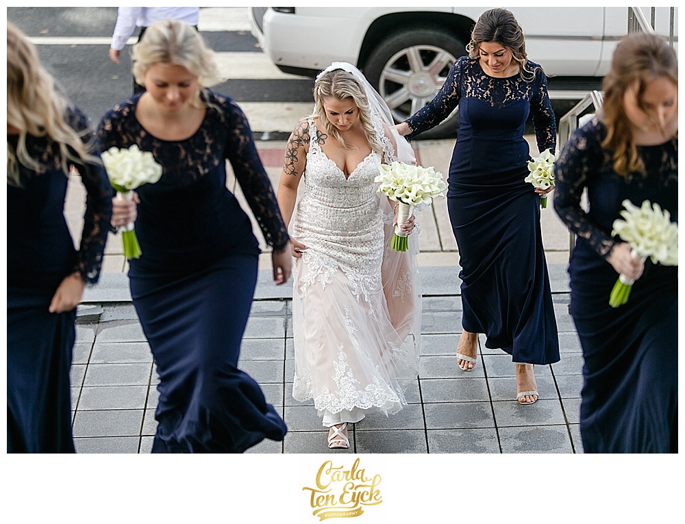 Bride in Stella York wedding gown walks up church stairs for her wedding ceremony in CT