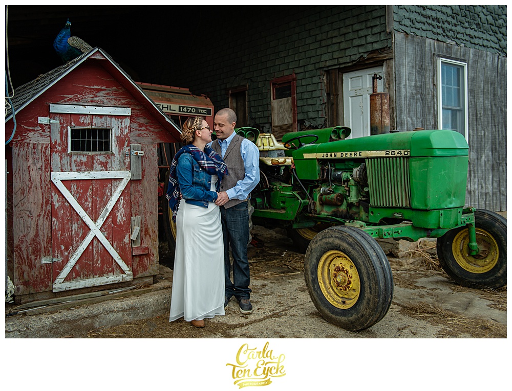 Birde and groom stand with a peacock and a John Deere tractor at Cold Spring Farm in Colchester CT