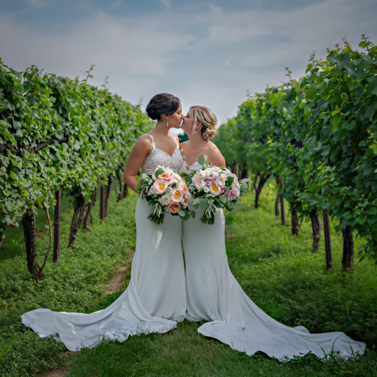 Two bride kiss in the vineyard at their wedding at Jonathan Edwards Winery