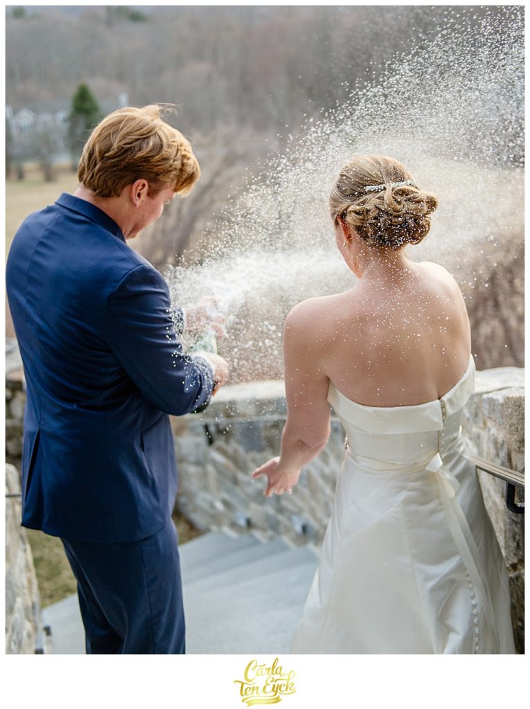Bride and groom pop champagne at their wedding at Le Chateau South Salem NY