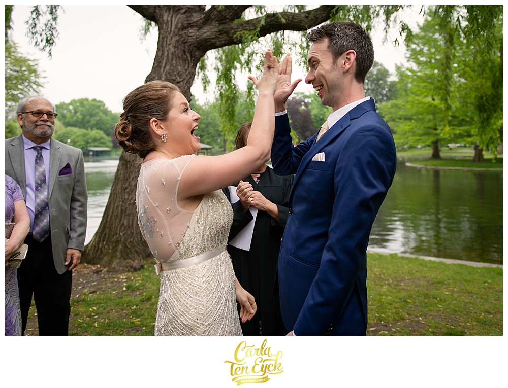 Bride and groom high five after getting married at the Boston Public Gardens in Boston MA