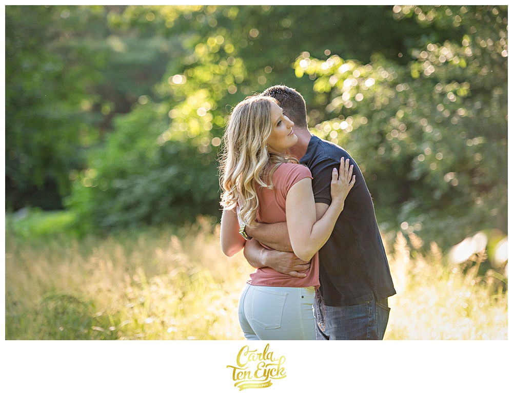 Couple hugs during their engagement session in a field in Elizabeth Park in Hartford CT