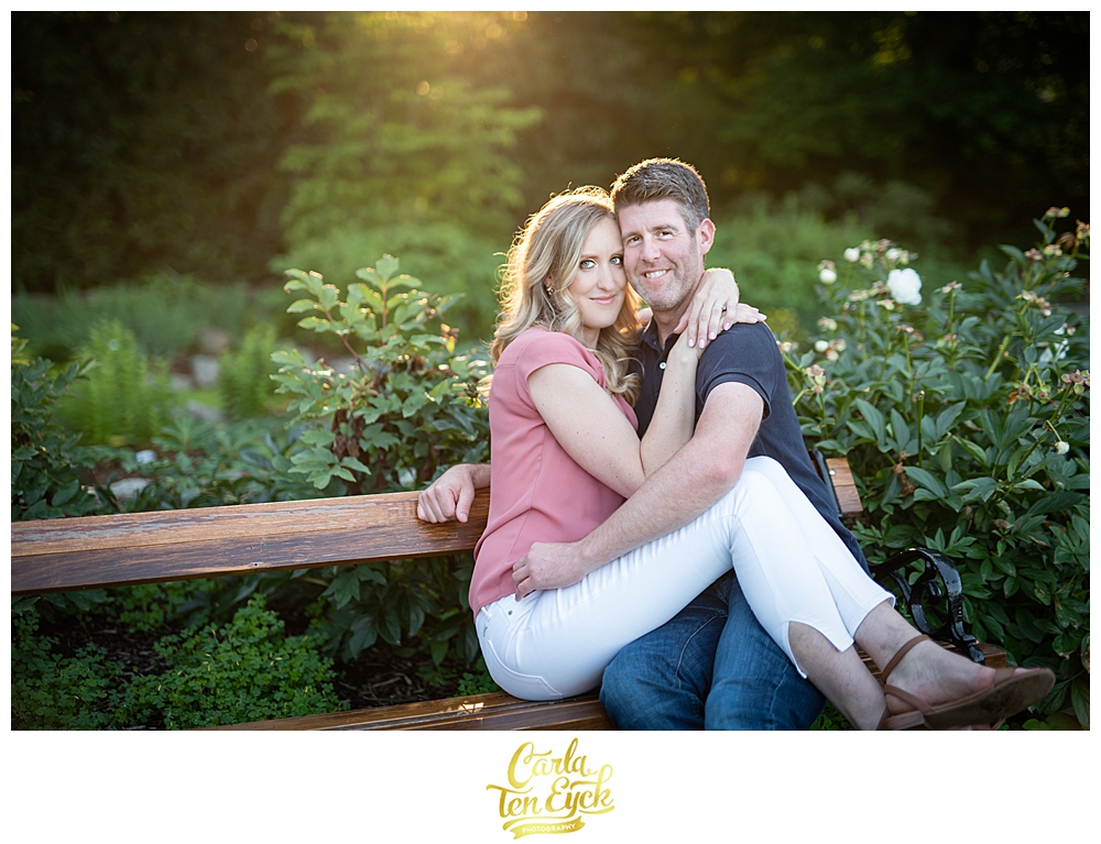 Couple snuggles on a bench during golden hour at Hartford's famous rose garden at Elizabeth Park