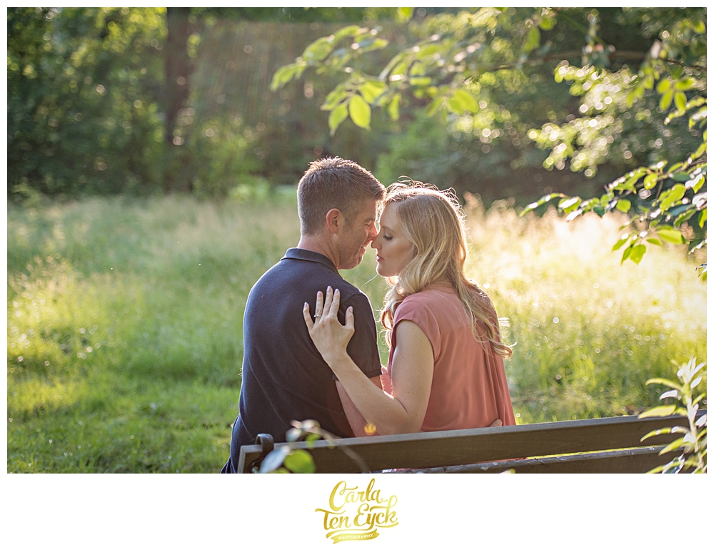 A couple snuggles on a bench in the later afternoon light at Elizabeth Park in Hartford CT
