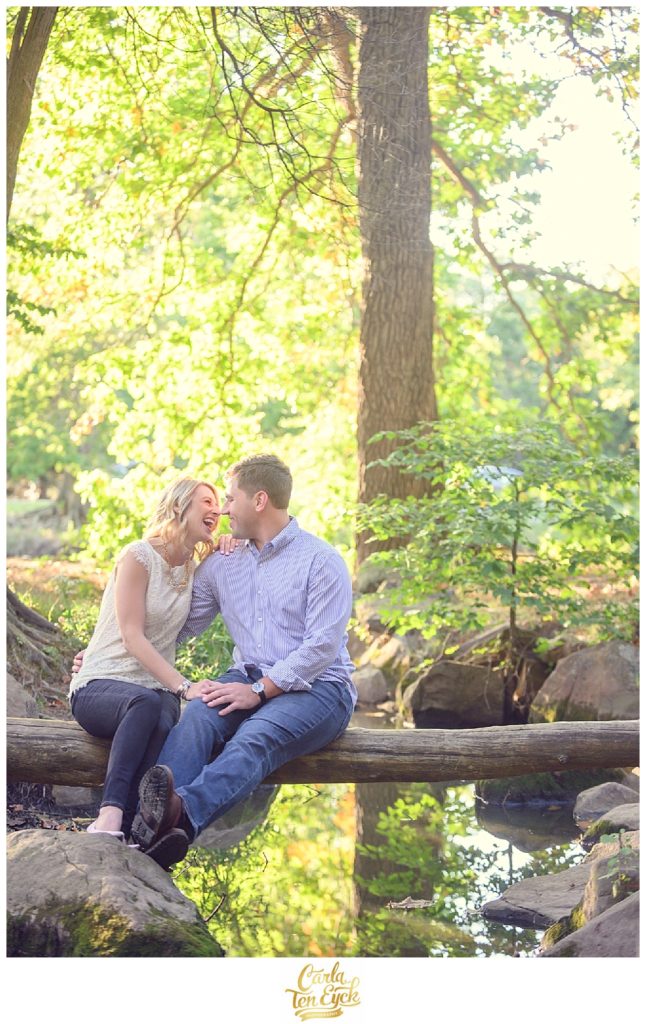 A couple laughs in a creek at Elizabeth Park in Hartford CT during their CT engagement