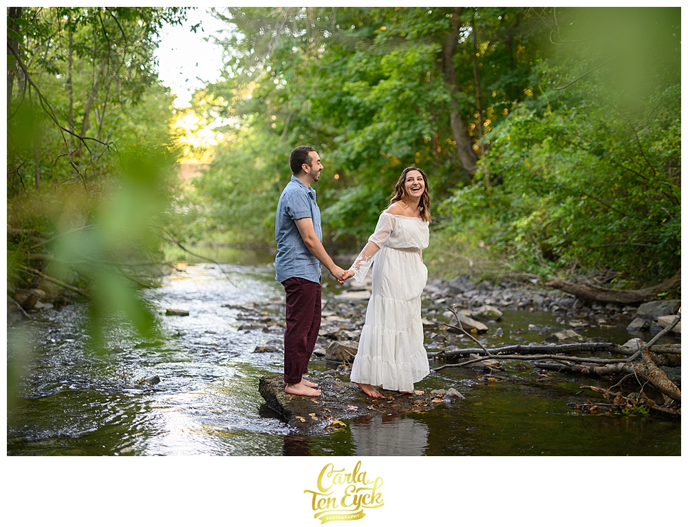 A couple laughs during their engagement session in the Hog River in hartford CT