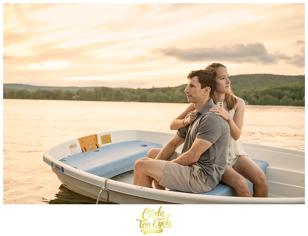 A couple cuddles in a boat on Lake Waramaug CT during their engagement session