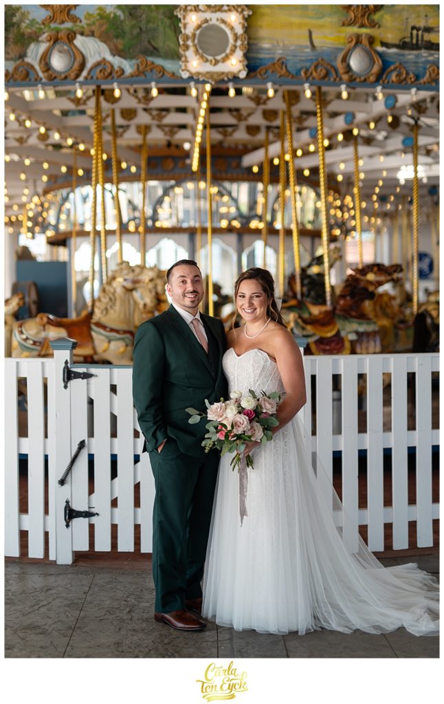 A bride and groom pose for photos at their wedding at Lighthouse Point Park in New Haven CT in the carousel