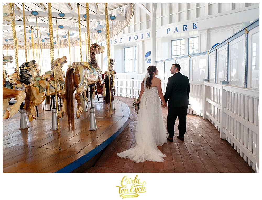 A bride and groom pose for photos at their wedding at Lighthouse Point Park in New Haven CT in the carousel