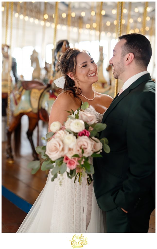 A bride and groom pose for photos at their wedding at Lighthouse Point Park in New Haven CT in the carousel