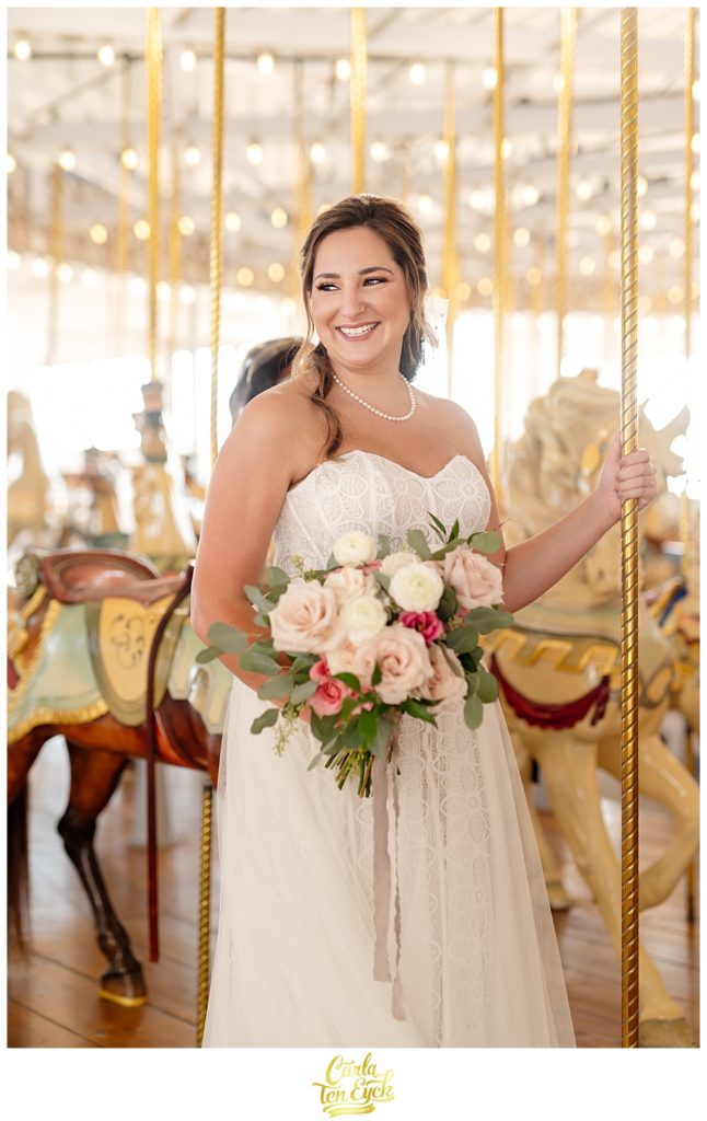 A bride poses on the carousel for photos at her wedding at Lighthouse Point Park in New Haven CT 