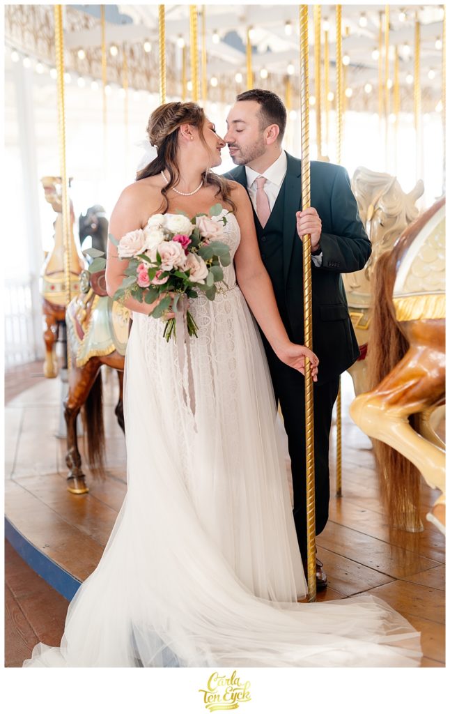 A bride and groom pose on the carousel for photos at their wedding at Lighthouse Point Park in New Haven CT