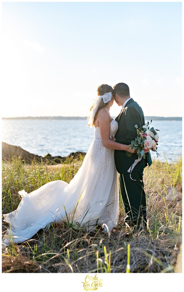 A bride and groom pose for pictures on the beach after their wedding at Lighthouse Point Park in New Haven CT