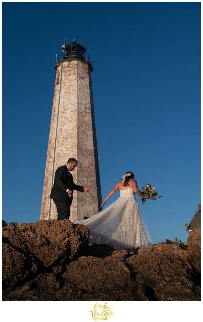 A bride and groom pose for pictures on the beach after their wedding at Lighthouse Point Park in New Haven CT