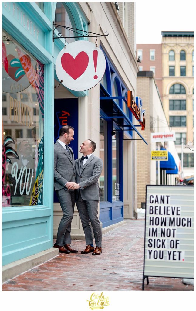 Two grooms pose outside Hartford Prints on Pratt Street in Hartford on their wedding day