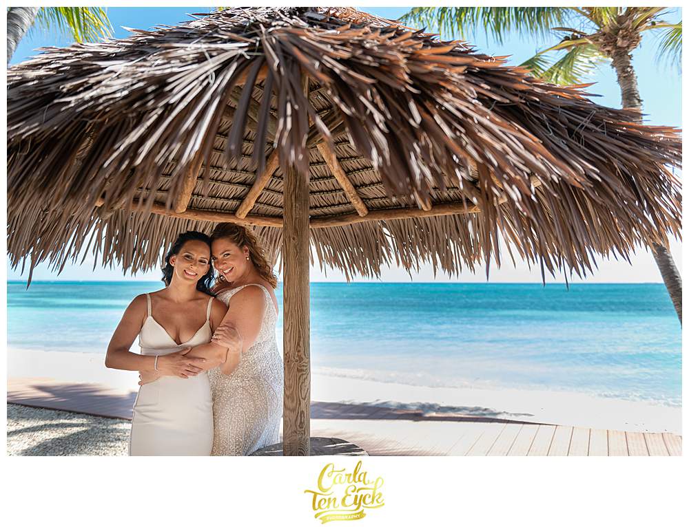 Two brides cuddle for photos at their Aruba Wedding on the beach