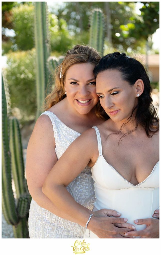 Two brides pose by cactus for their Aruba wedding at the Tamarijn Resort