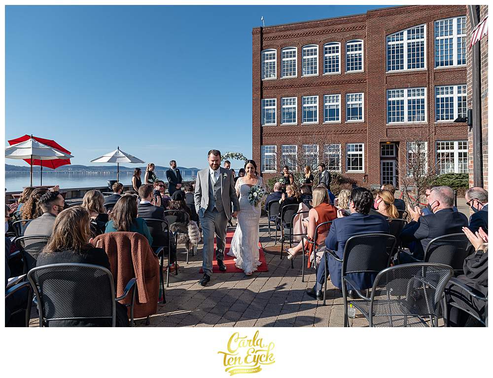 A bride and groom walk down the aisle at their wedding at Red Hat on the River in Irvington NY