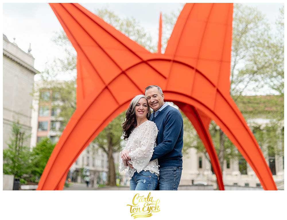 A couple snuggles in front of the Stgosaurus sculpture during their downtown Hartford engagement, Hartford CT