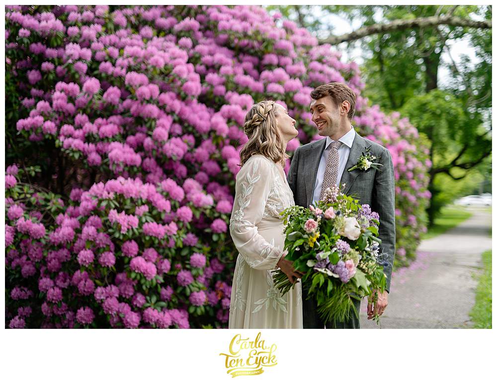 A bride and groom pose for photos by a giant rhododendron after their Litchfield wedding in Litchfield CT