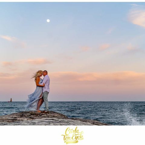 A couple poses on the rocks of Great Island Common in Portsmouth New Hampshire during their engagement session