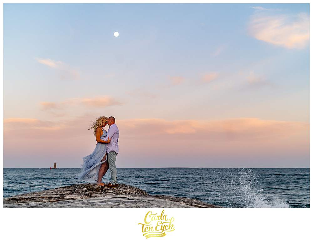 A couple poses on the rocks of Great Island Common in Portsmouth New Hampshire during their engagement session