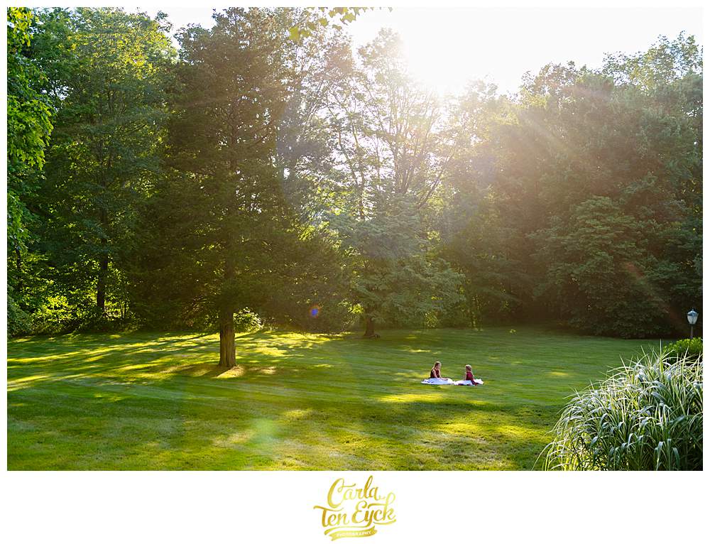 Two flower girls sit in the sunlight during cocktail hour at a Bill Miller's Castle wedding in Branford CT