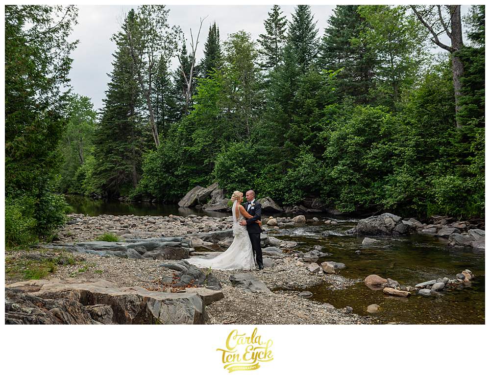 A couple poses for photos in a stream during their New Hampshire wedding.