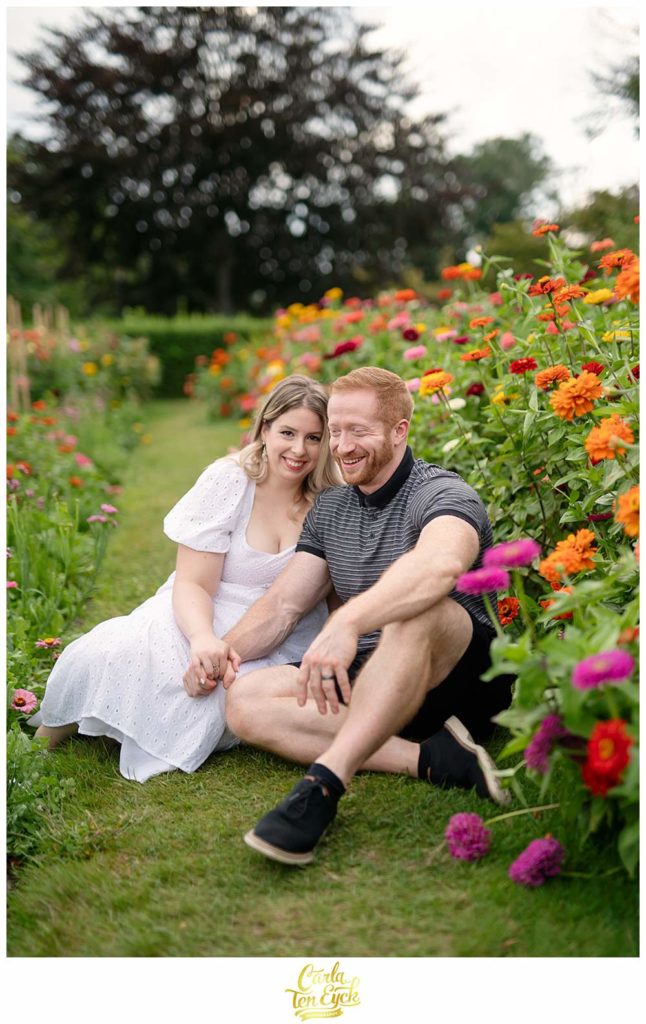 A couple laughs during their Harkness Park engagement session in the zinnia garden in Waterford CT