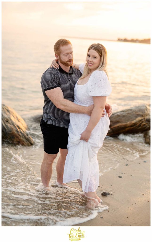 A couple plays in the waves at Harkness during their engagement session at Harkness Park in Waterford CT