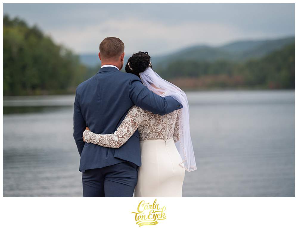 A couple embraces on the docks at their summer camp wedding at Camp Lenox in Otis MA