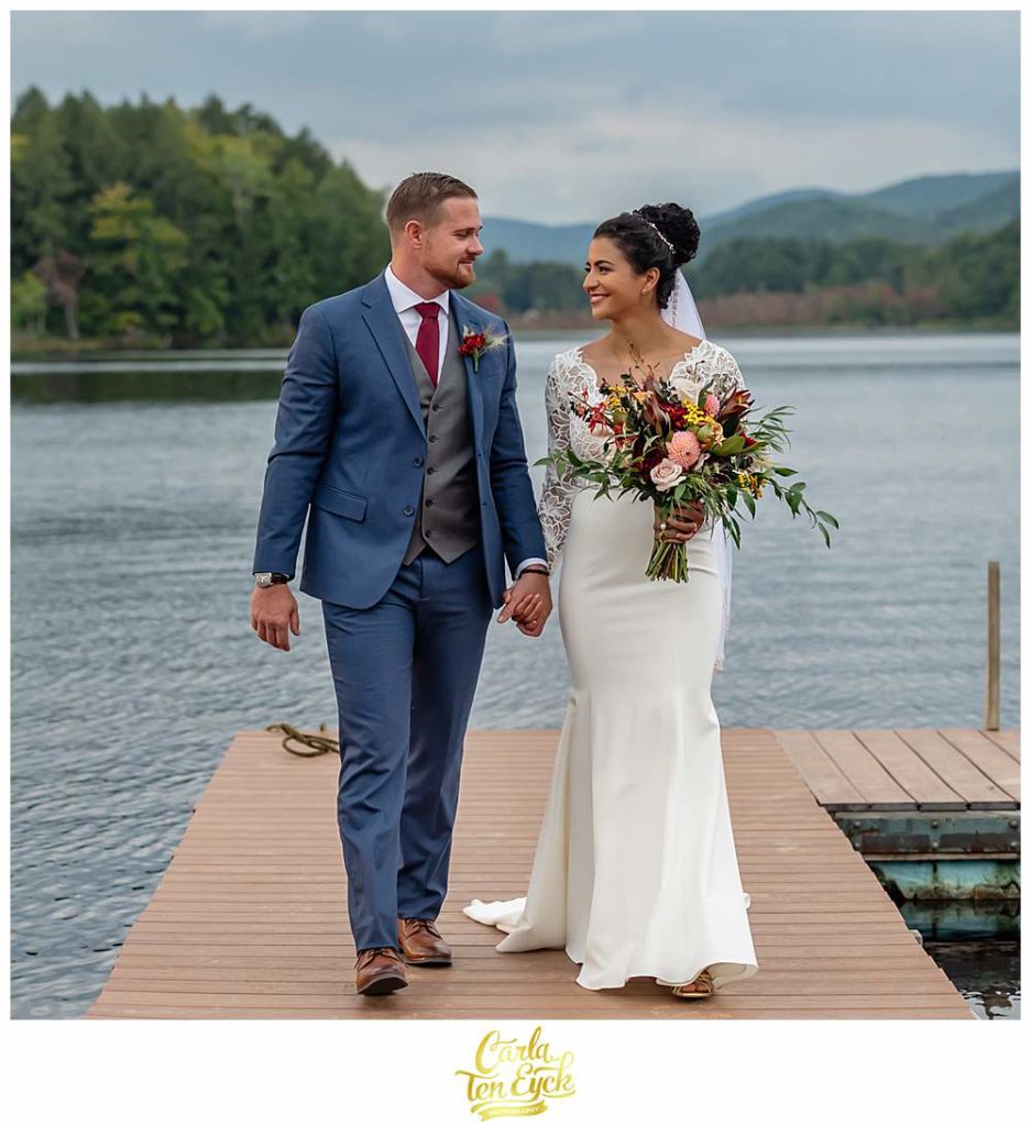 A bride and groom walk on the swim platform during their summer camp wedding at Camp Lenox in Otis MA