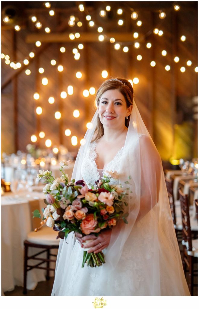 A bride basks in the glow of the Edison bulbs at her autumn Saltwater Farm vineyard wedding in Stonington CT