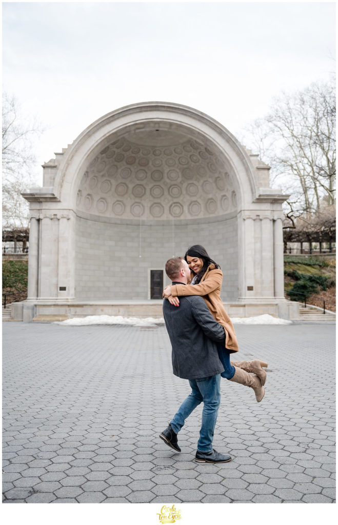 A couple dances in front of the iconic bandshell in Central Park during their winter engagement session