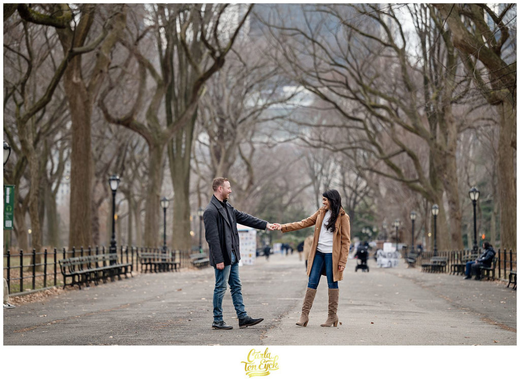 A couple walks along the iconic Mall in Central Park during their winter engagement session 