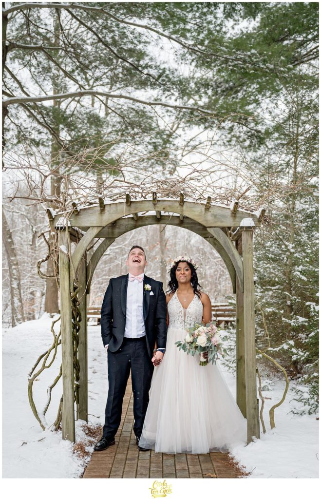 A couple laughs in the snow during their wedding at The Pavilion at Crystal Lake in Middletown, CT
